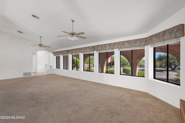 carpeted empty room featuring lofted ceiling, ceiling fan, and visible vents