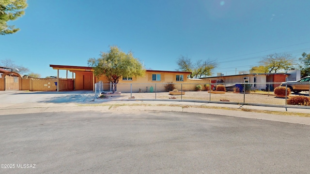 view of front of home featuring driveway, an attached carport, a fenced front yard, and a gate