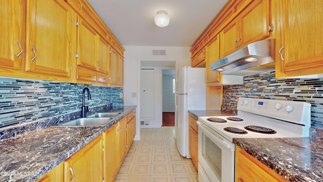 kitchen featuring visible vents, a sink, dark stone countertops, white appliances, and under cabinet range hood