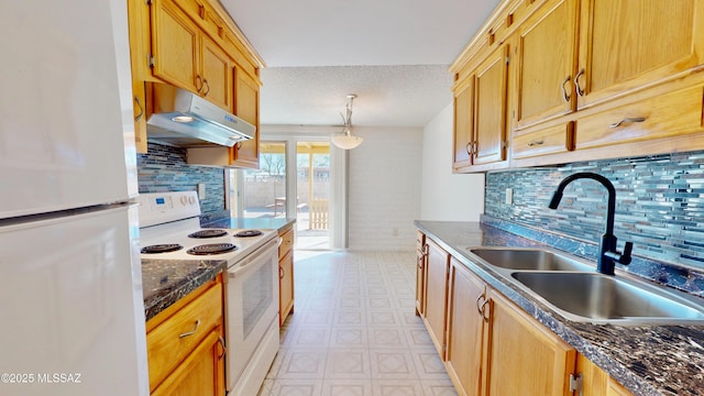 kitchen with under cabinet range hood, white appliances, a sink, light floors, and dark countertops