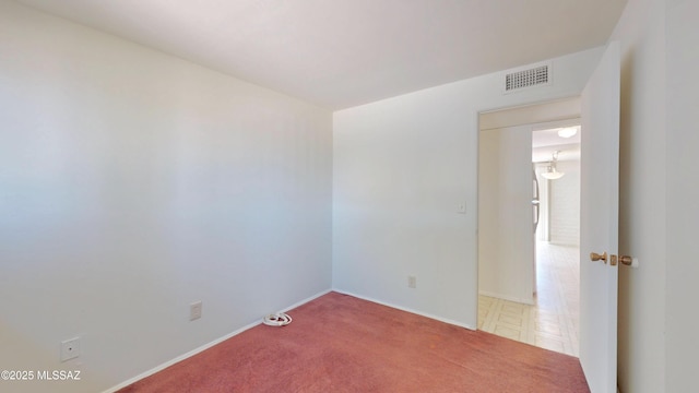 spare room with carpet floors, visible vents, and baseboards