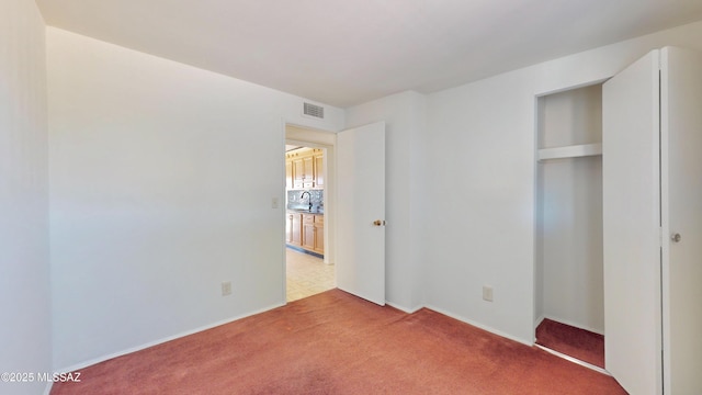 unfurnished bedroom featuring carpet, a closet, visible vents, and a sink