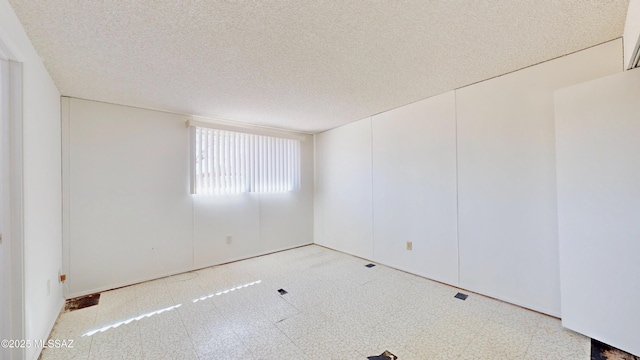 spare room with a textured ceiling and tile patterned floors