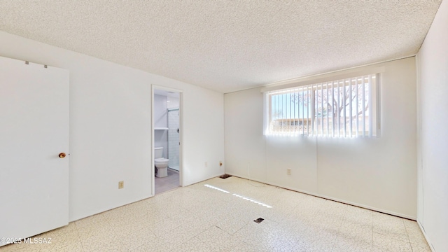 unfurnished room featuring a textured ceiling and tile patterned floors