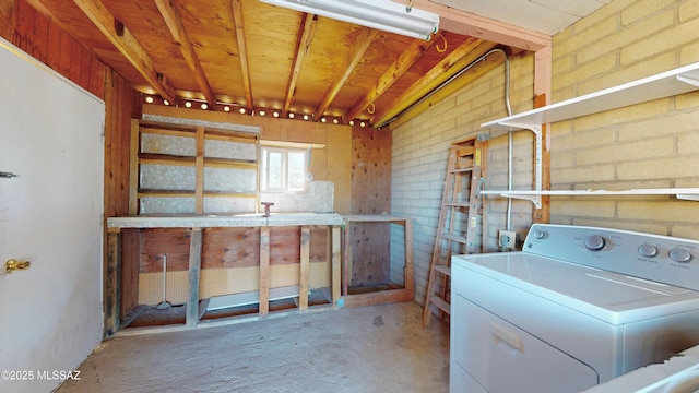 laundry area with laundry area, brick wall, and washer / dryer