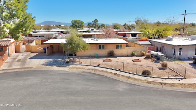 single story home with a fenced front yard, a mountain view, an attached carport, and concrete driveway