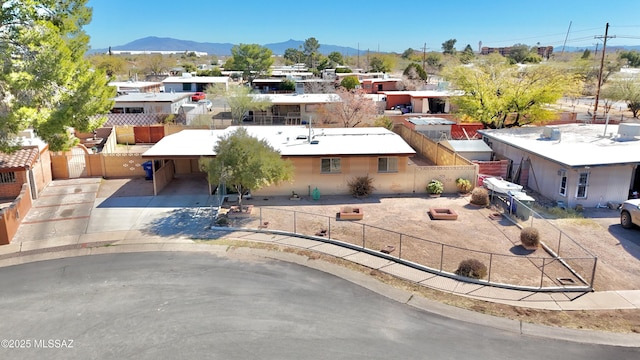 exterior space with a fenced front yard, an attached carport, a mountain view, and driveway