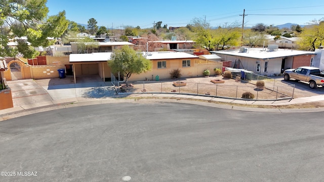 ranch-style house with concrete driveway, an attached carport, a fenced front yard, and a gate