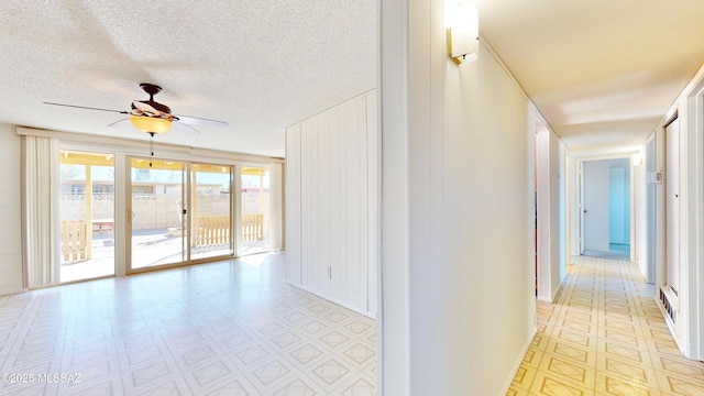 hallway with a textured ceiling and light floors