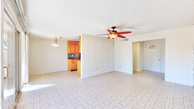 spare room featuring ceiling fan, light floors, a textured ceiling, and visible vents