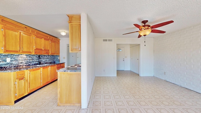 kitchen with brick wall, visible vents, a sink, and light floors