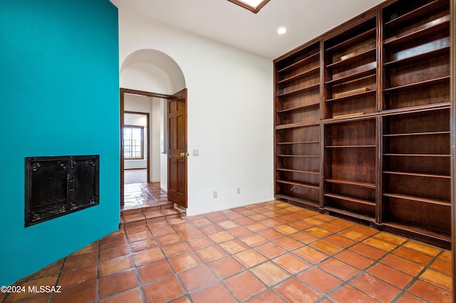 spare room with built in features, arched walkways, tile patterned flooring, and recessed lighting