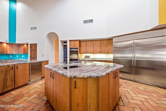 kitchen featuring stainless steel appliances, arched walkways, visible vents, and a high ceiling