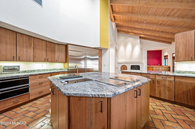 kitchen featuring cooktop, a center island with sink, wood ceiling, stainless steel built in fridge, and a warming drawer