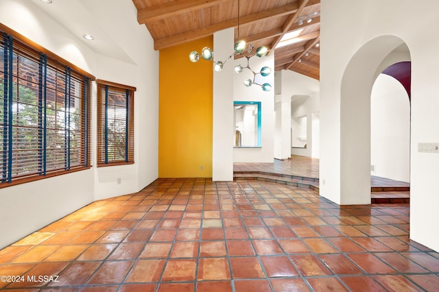 empty room with arched walkways, high vaulted ceiling, wooden ceiling, beamed ceiling, and tile patterned floors