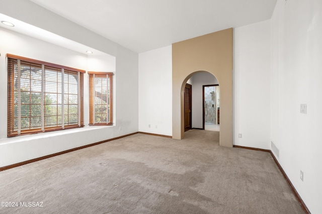 spare room with baseboards, visible vents, arched walkways, carpet flooring, and recessed lighting