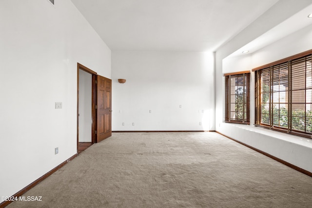 unfurnished room with light carpet and baseboards