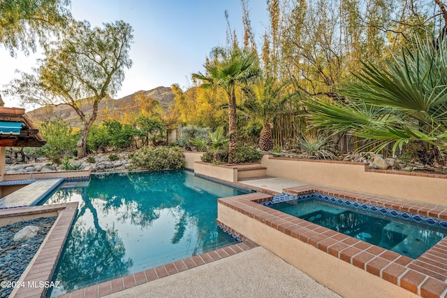 pool with a mountain view and an in ground hot tub