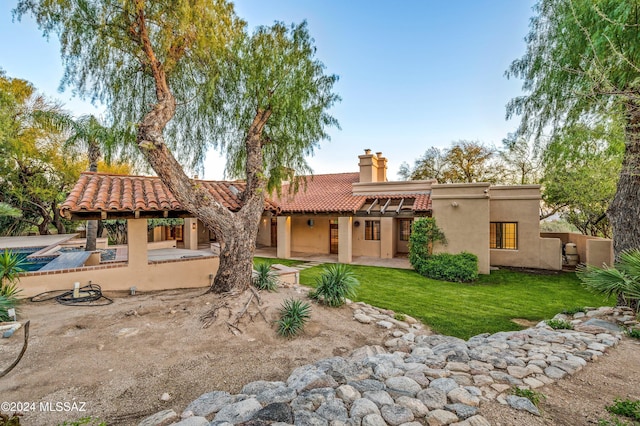 back of property featuring a chimney, a patio area, a tile roof, and stucco siding