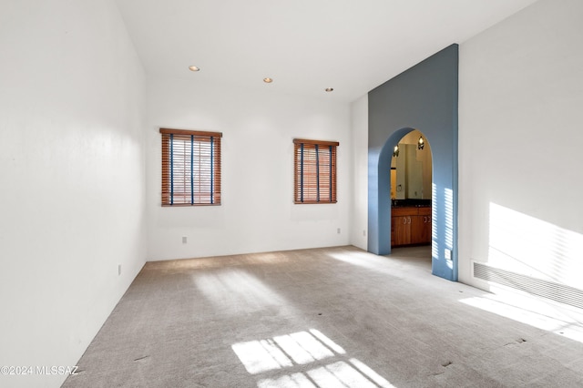 carpeted spare room featuring arched walkways and recessed lighting