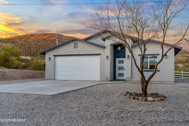 view of front facade with driveway, an attached garage, fence, and stucco siding