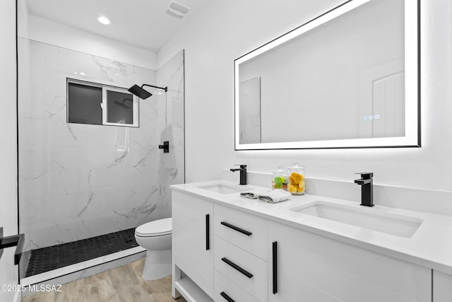 full bathroom with a marble finish shower, a sink, toilet, and wood finished floors