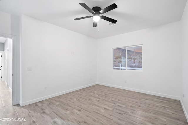 empty room with light wood-style floors, visible vents, baseboards, and a ceiling fan