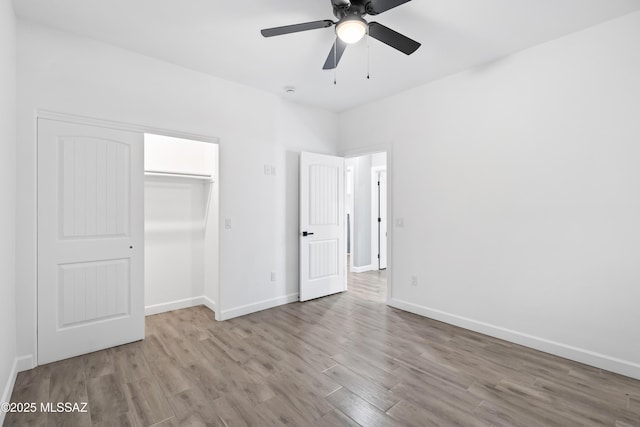 unfurnished bedroom featuring a closet, wood finished floors, a ceiling fan, and baseboards