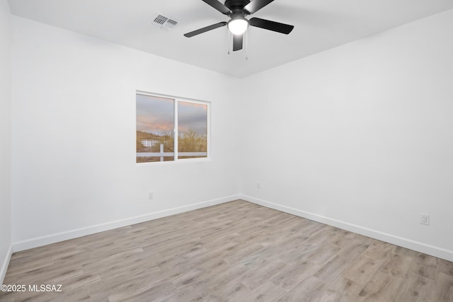 empty room featuring baseboards, visible vents, and wood finished floors