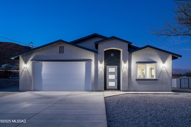 ranch-style house featuring a garage, concrete driveway, a storage shed, and stucco siding