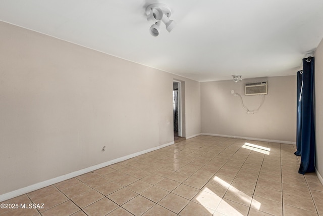 spare room featuring a wall mounted AC, light tile patterned flooring, and baseboards