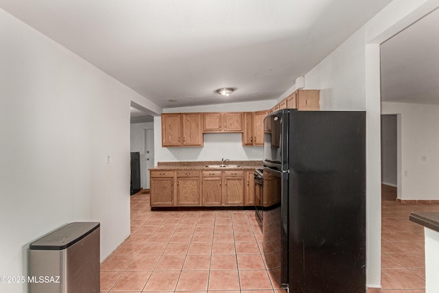 kitchen with light tile patterned floors, light countertops, a sink, and freestanding refrigerator