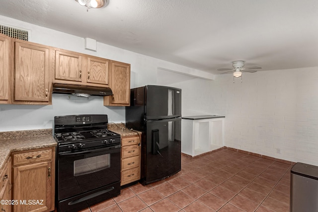 kitchen featuring light tile patterned floors, ceiling fan, brick wall, under cabinet range hood, and black appliances