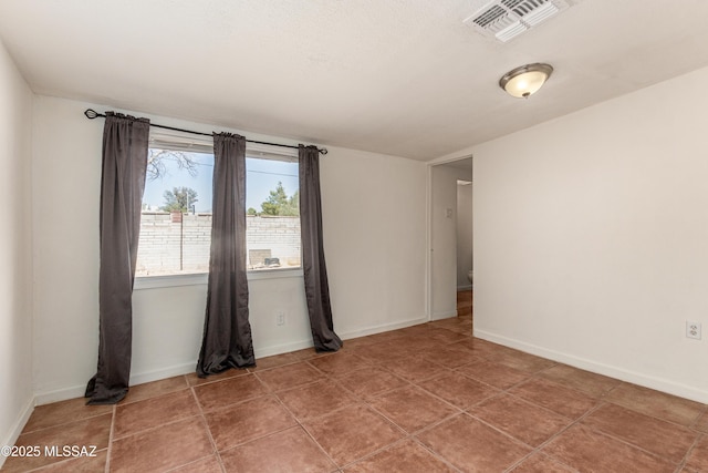 tiled spare room featuring visible vents and baseboards