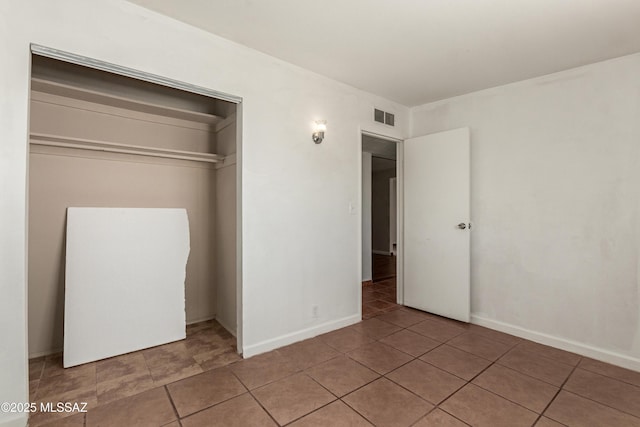 unfurnished bedroom featuring tile patterned flooring, a closet, visible vents, and baseboards