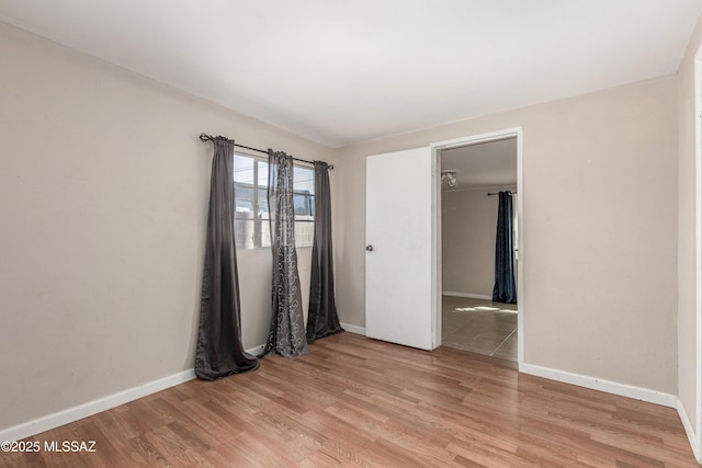 unfurnished room featuring baseboards and light wood finished floors