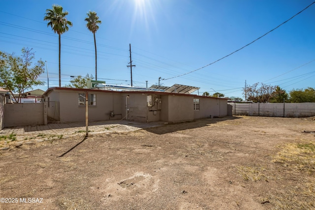 rear view of house featuring fence and stucco siding