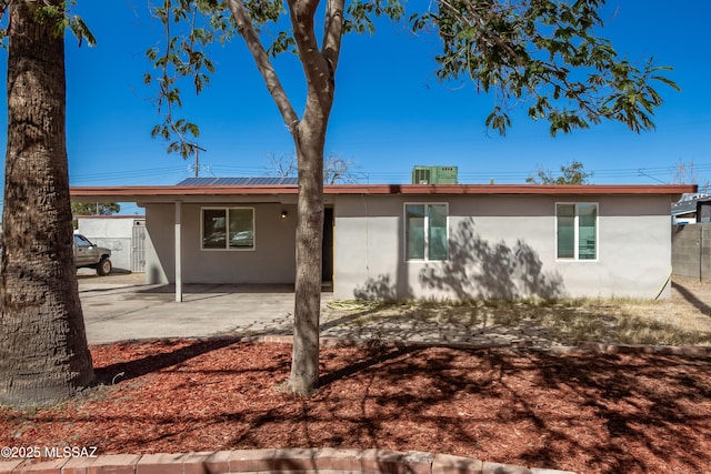 rear view of house with a patio area, fence, and stucco siding