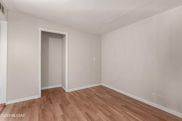 empty room featuring light wood-type flooring, visible vents, and baseboards