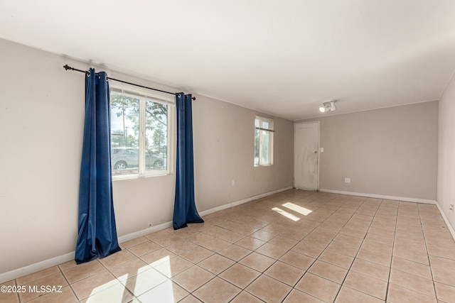 spare room featuring light tile patterned floors and baseboards