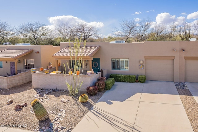 southwest-style home with a garage, concrete driveway, a tiled roof, and stucco siding