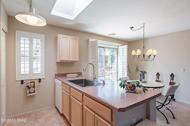 kitchen with white dishwasher, a peninsula, a skylight, a sink, and visible vents