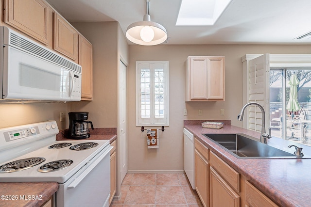 kitchen with a skylight, light tile patterned floors, a sink, white appliances, and baseboards