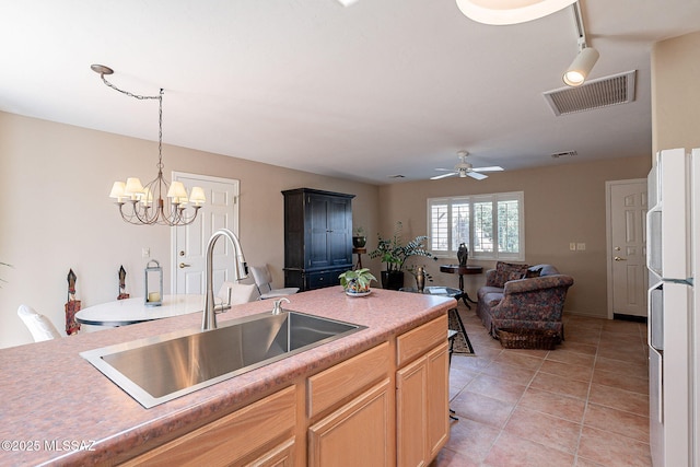 kitchen with light countertops, freestanding refrigerator, visible vents, and a sink