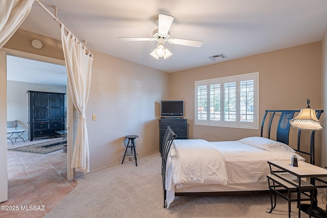 bedroom featuring light tile patterned floors, baseboards, visible vents, light colored carpet, and ceiling fan