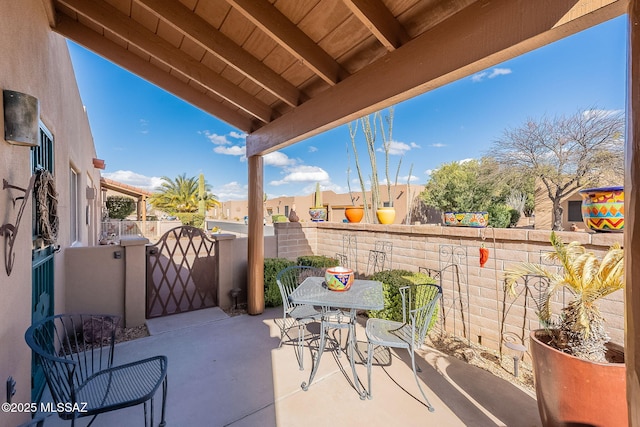 view of patio with outdoor dining area, fence, and a gate