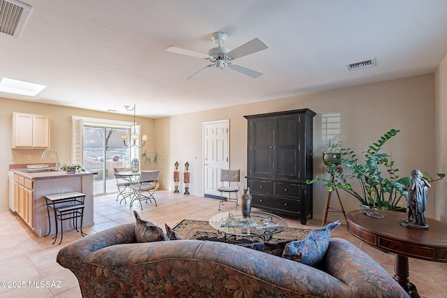 living room featuring a skylight, baseboards, visible vents, and ceiling fan with notable chandelier