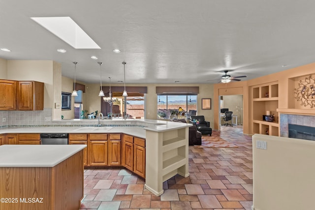 kitchen with built in features, a tile fireplace, open floor plan, a peninsula, and a sink