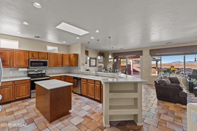 kitchen featuring stainless steel appliances, a peninsula, a skylight, visible vents, and open floor plan