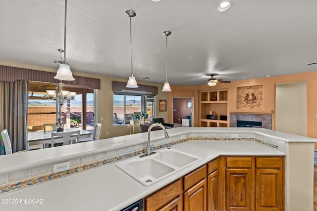 kitchen with built in shelves, a sink, open floor plan, light countertops, and pendant lighting